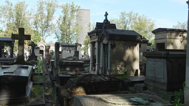 Ancient Parisian cemetery Montparnasse. Tombstones and crypts on graves. Old burial in the shade of trees. Memory of ancestors, peace of mind