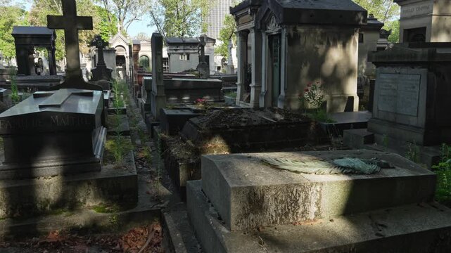 Ancient Parisian cemetery Montparnasse. Tombstones and crypts on graves. Old burial in the shade of trees. Memory of ancestors, peace of mind