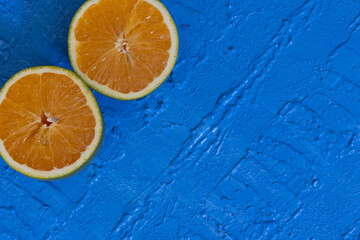 Two halves of an orange positioned side by side diagonally on a blue background