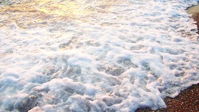 Waves gently lap at shore during stunning sunset over ocean. Golden sunlight reflects off waves as they roll onto shore, creating tranquil atmosphere at sunset by sea. Montenegro summer Canj