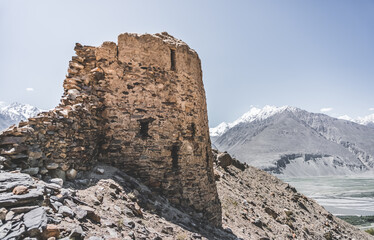 Fototapeta premium Remains of the ancient fortress of Yamchun in the Tien Shan mountains in Tajikistan in the Pamirs, ruins of a fortress fort made of stone on the background of mountains