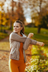 elegant woman in fitness clothes in park stretching