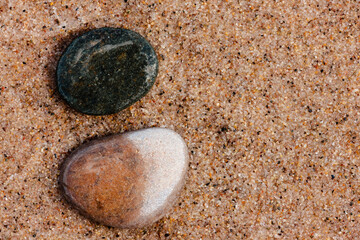 Two stones, one starting to dry, lay on the beach at Kohler-Andrae State Park, Sheboygan, Wisconsin in late June