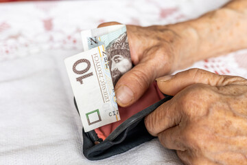 Poland money, An old lady takes out 10 Polish zlotys from an old-fashioned purse. Concept, The situation of pensioners in Poland.