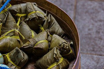 Close-up of traditional Indonesian Bakcang, wrapped in banana leaves and tied with yellow strings,...