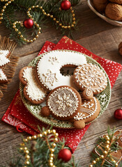 Homemade gingerbread Christmas cookies decorated with white icing on a plate with spruce tree branches