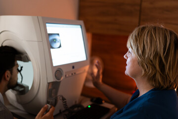Good looking female doctor ophthalmologist is checking the eye vision of handsome middle age man in...
