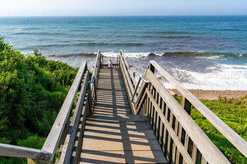 Fototapeta premium Wooden staircase leading down to the beach at Mohegan Bluffs, Block Island, Rhode Island, USA. August 2024. 