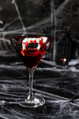 Glass of delicious red cocktail for Halloween on dark background