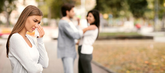 Infidelity. Sad Girl Crying Seeing Her Cheating Boyfriend Hugging Other Woman In Park. Selective Focus