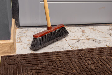 A broom brush at the front door. Dirt and sand from the street