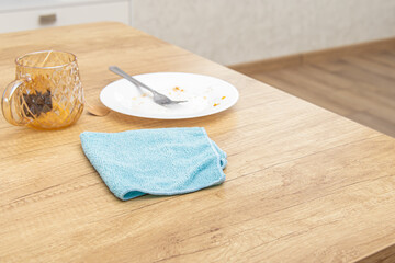 Dirty dishes and cleaning cloth on wooden table. Cleaning the kitchen after meals. Free space for text