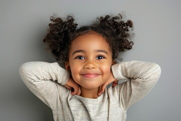 A young girl with curly hair smiling and posing for the camera
