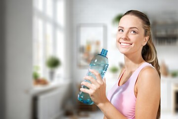 Happy young sporty woman Drinking water after fitness