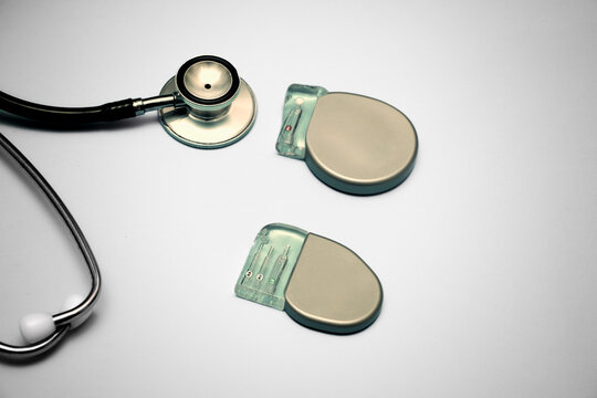 Implantable pacemaker devices such as ICD and CRT devices placed along with a stethoscope on a gradient green background.