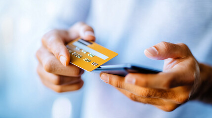 A close-up view of hands holding a smartphone and a credit card, illustrating the process of making a digital payment. The image emphasizes the ease and accessibility of online tra
