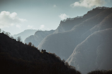 Landscape with beautiful fog in forest on hill or Trail through a mysterious winter forest with autumn leaves on the ground. Road through a winter forest. Magical atmosphere. Azerbaijan nature