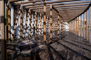 A wooden pergola with a swing in the middle of it