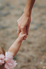 Happy family, mother with little girl daughter holding hands together walking outdoors. Close-up photo, parenthood concept.