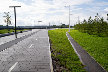 This modern urban pathway features beautiful green landscaping and elegant lamp posts for added charm
