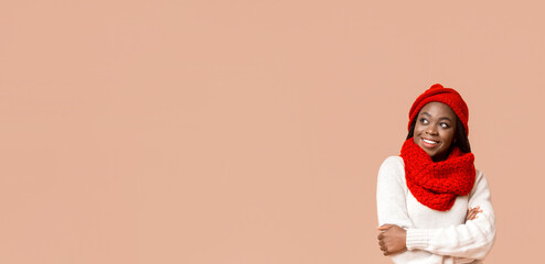 Confident smiling african woman in knitted red set looking at empty space over beige background