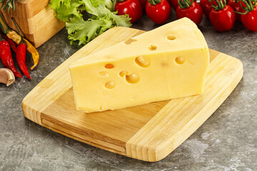 Swiss Maasdam cheese triangle over board