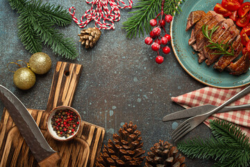 Festive Christmas dinner boarder background with space for text with roasted duck breast fillet with golden crispy skin and tomato salad, Xmas decorations with fir tree, cones, red berries..