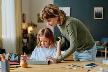 Fototapeta premium Young Caucasian mom helping her daughter to gain new level in video game