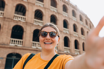 Beautiful 30s female walking in Valencia. Young traveling woman taking selfie outdoors. Concept of travel, tourism and vacation in city. High quality photo