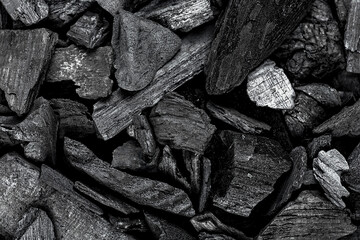 Black lump charcoal pieces as background, top view. BBQ grill coal.