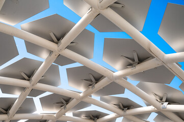 Close-up of a modern architectural structure featuring hexagonal panels arranged in a grid pattern,...