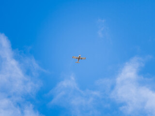 Small ultralight airplane with overhead wing and single propeller flying in sunset sky.