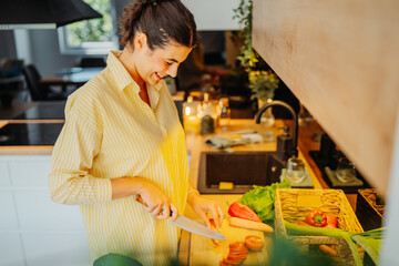 Young caucasian woman cutting vegetables in the kitchen

