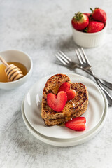 Whole grain heart shaped toast with fresh strawberries and honey