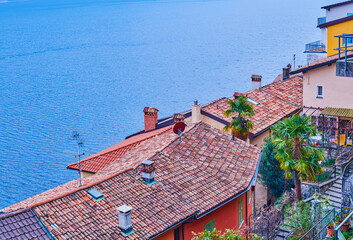 Flag of Lugano city and the old tile roofs in medieval village Gandria on the shore of Lake Lugano, Switzerland