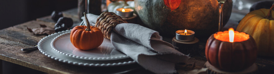 Cozy festive holiday table decor, home family Thanksgiving dinner. Traditional event, elegant natural rustic decoration. Countryside style. Burning candles, floral centrepiece pumpkin banner