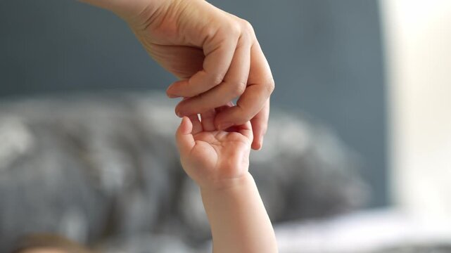 A close-up shot of a mother&rsquo;s fingers gently touching her newborn&rsquo;s tiny fingers, capturing a tender and intimate moment.