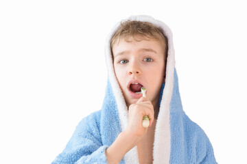 small child, boy in a blue terry robe with a toothbrush on white. A child brushes his teeth. Healthcare and dental care