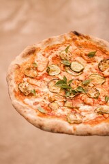 Pizza de vegetales con albahaca y fondo beige difuminado. 