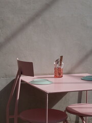 Cafetería con pared de concreto, mesas rosas y platos de colores pastel 