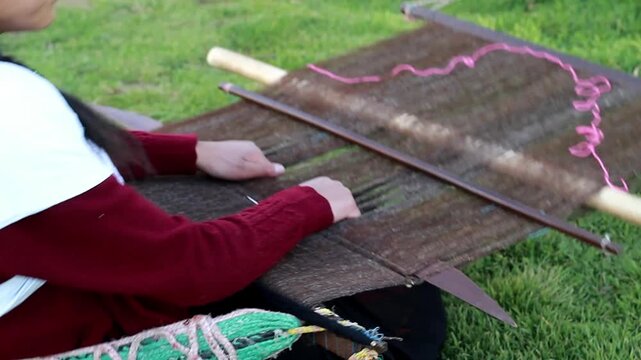 Mujer peruana campesina atractiva  trabajando en la producci&oacute;n tradicional de tejido de manta lana hecha a mano.Cercano al tejido en Per&uacute;.