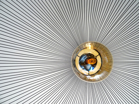 Abstract image of a suspending light with yellow bumb and black metalic lines. Monocrome background lines. close-up