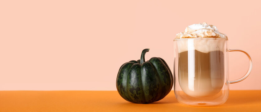 Glass cup of tasty pumpkin latte on colorful background