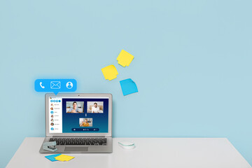 Modern laptop on table and sticky notes on wall