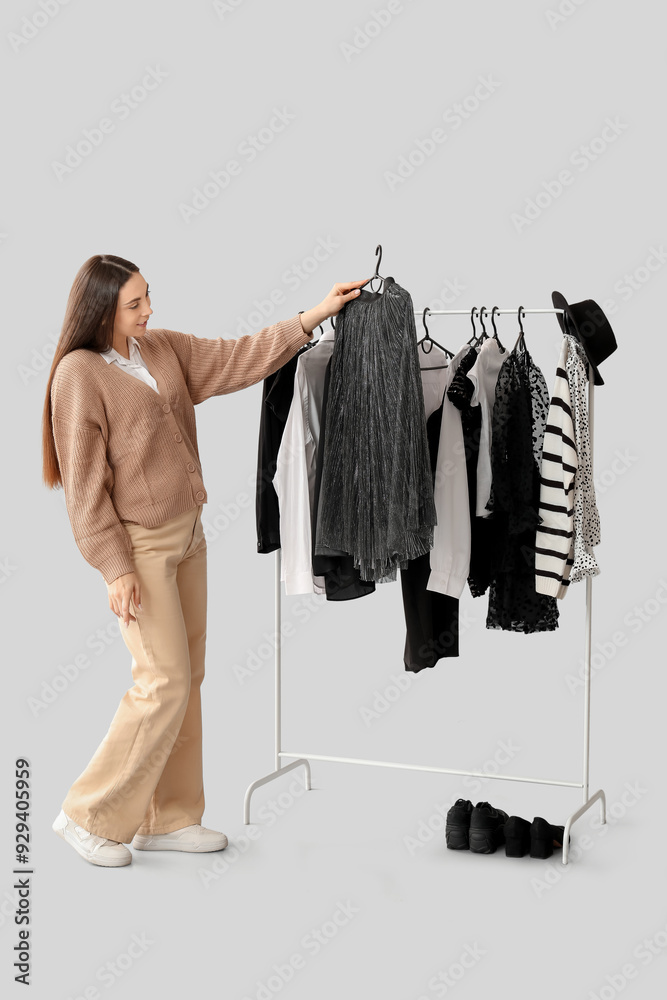 Sticker Happy female stylist with clothes on rack against grey background