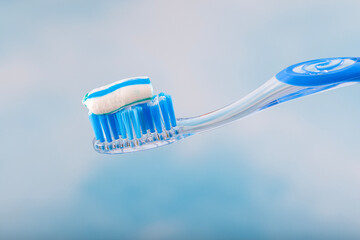 Toothbrush and toothpaste, Squeezing toothpaste onto toothbrush. Applying toothpaste on brush against blurred background, closeup.