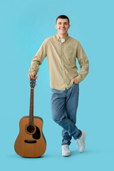 Naklejka premium Handsome young man with guitar on blue background