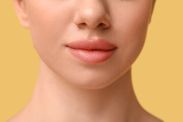 Young woman with beautiful lips on yellow background, closeup