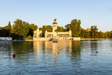 Obraz premium Retiro Park, Madrid, Spain. Crystal Palace, lake with swans, glass structure, architecture. Lake and temple on the horizon, fountains and decorated with colorful plants and flowers, family leisure.