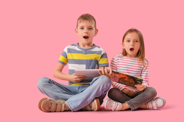 Shocked little kids reading book on pink background
